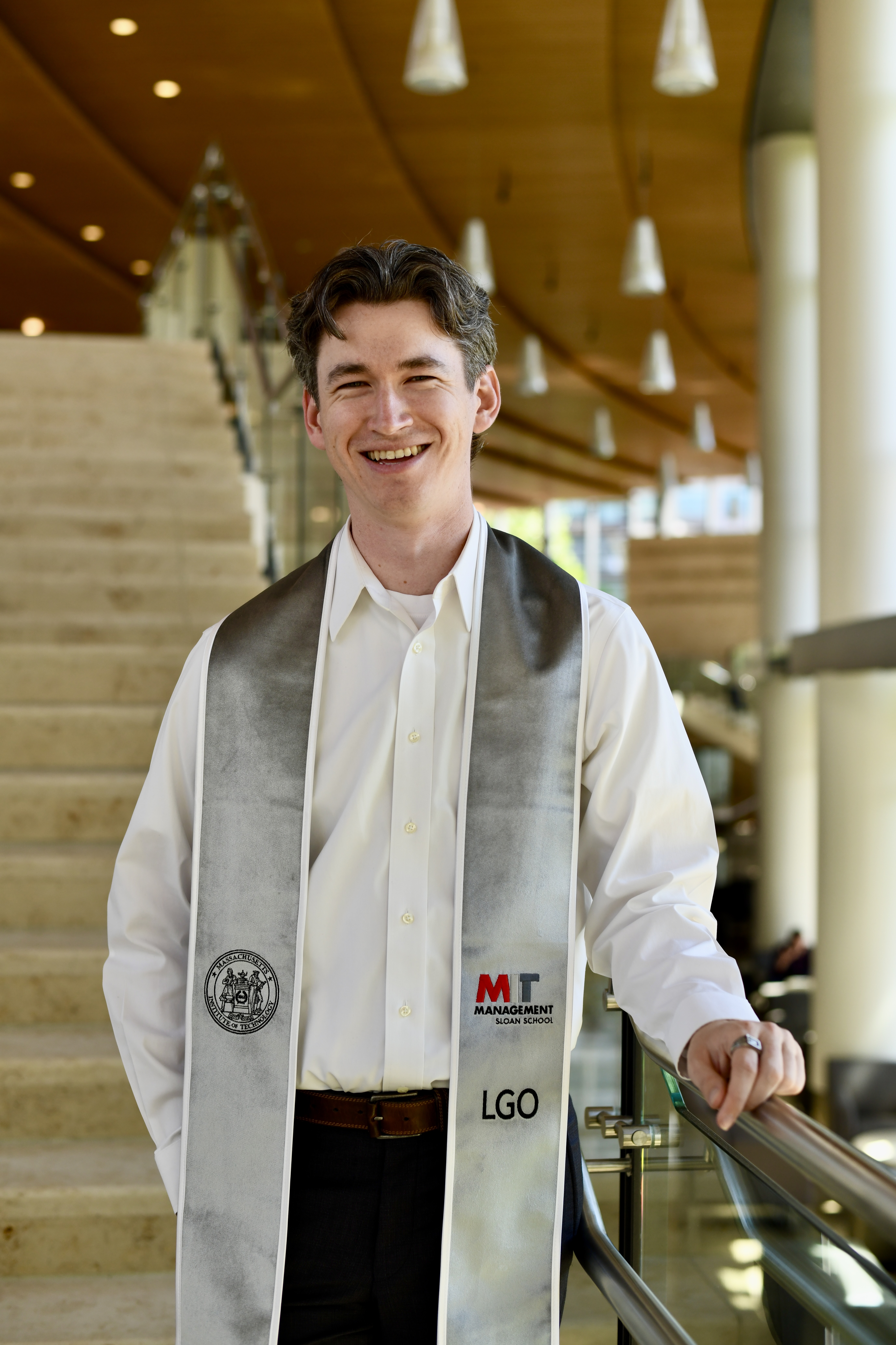John Zeeman in MIT Sloan's atrium wearing his Leaders for Global Operations graduation stole